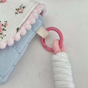 Detailed macro view of floral cotton storage bag with pink pompom trim and braided handle