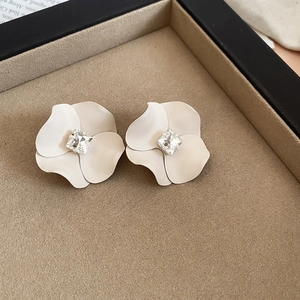 Detailed close-up of cream white floral stud earrings with a square rhinestone center