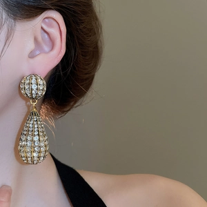 Close-up of golden teardrop earrings with crystal pavé on a model for a vintage look