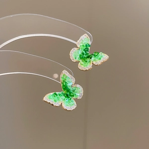Macro shot of 18k gold plated butterfly stud earrings with sparkling green crystals