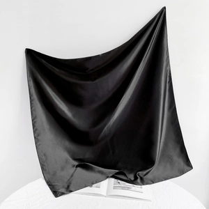 Artistic drape of glossy black satin square scarf showing smooth silk texture and sheen