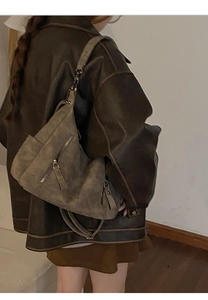 Detail of vintage suede tote bag with metal zipper and tassel on model's shoulder