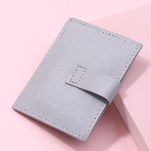 Close-up of grey litchi texture card holder with snap closure on a pink background