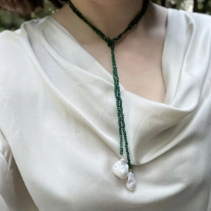 Detail of a long beaded tie-style necklace with green spinel and white baroque pearls
