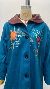 Close-up of floral print and brown contrast collar on navy long-sleeve woolen coat
