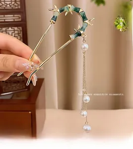 Détail d'épingle à cheveux dorée en U avec motif bambou vert et pompons de perles