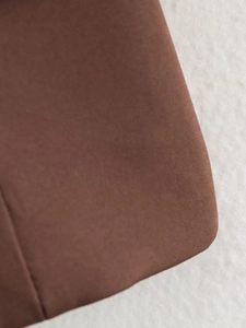 Detailed macro view of dark brown fabric texture and fine stitching on a vintage skirt suit