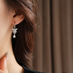 Gros plan sur une boucle d'oreille papillon en zircon avec pendentif poire sur modèle