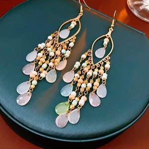 Macro shot of Bohemian beaded tassel earrings with pink and green crystal drops on velvet