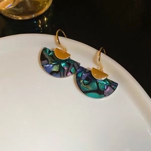 Macro detail of fan-shaped abalone shell earrings with iridescent colors and gold hooks