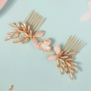 Close-up of golden bridal hair comb with pink leaves and central pearl flower