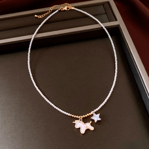 Detailaufnahme der Perlenkette mit goldenem Pony-Anhänger und Stern-Zirkon-Charm