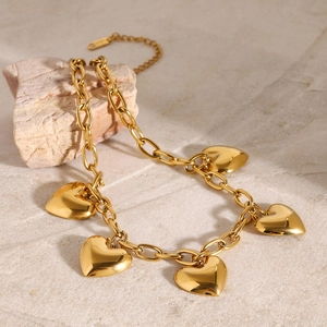Polished gold heart charm necklace with thick link chain on a textured stone base
