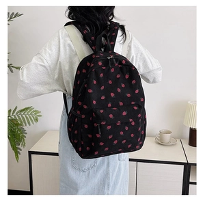 Black corduroy backpack with strawberry prints shown in a cozy home setting