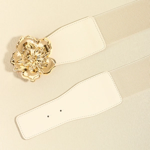 Détail d'une ceinture élastique crème avec une grande boucle fleurie en métal doré