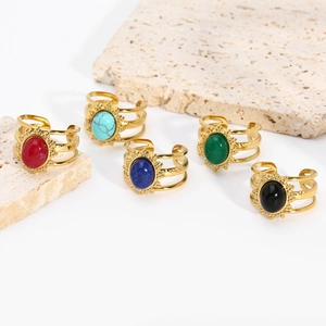 Macro view of five vintage gold rings featuring colorful natural stones on stone slabs