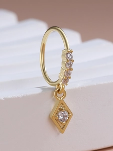 Macro shot of gold-plated geometric rhombus pendant earrings with sparkling zircon stones
