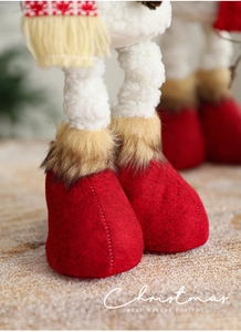 Close-up of plush snowman doll legs featuring red felt boots and faux fur trim details
