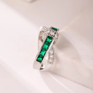 Close-up of crisscross silver ring with square emerald-green and white cubic zirconia