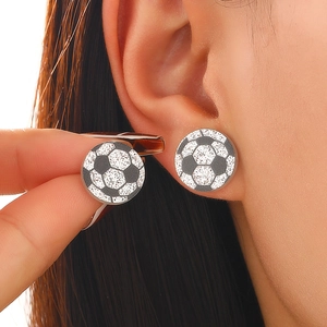 Vue macro de boucles d'oreilles ballon de foot avec cristaux noirs et blancs portées