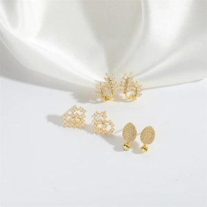 Golden leaf, heart, and zircon earring set displayed on elegant white silk background