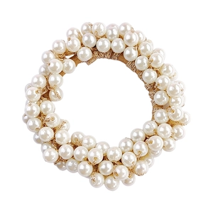 Close-up detail of white pearls and golden metallic threads on a flexible elastic hair tie