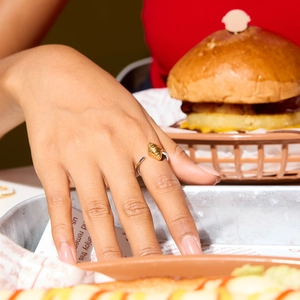 Vue macro d'un charm croissant en or 18 carats sur une bague ouverte en acier argenté