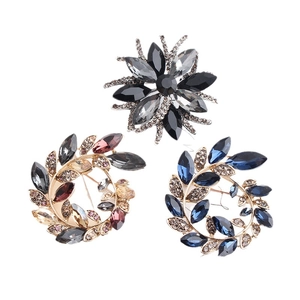 Three elegant crystal floral brooches in black, red, and blue with gold finish