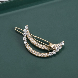 Golden moon and star hair clip with sparkling rhinestones on a minimalist green surface