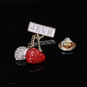 Detail of a dual heart brooch featuring rhinestones and a 4EVR nameplate on a reflective base