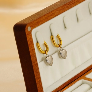 Detail of two-tone heart earrings with gold hoop and silver pendant in wooden box