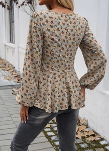 Detail of floral puff sleeve blouse with a slim waist and flared hem on a model outdoors