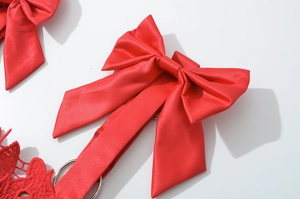 Close-up of bright red satin bow accessory with silver metal ring and silky texture