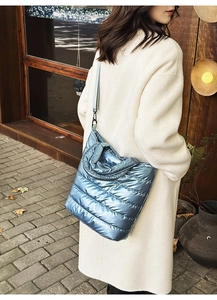 Blue quilted tote bag with metallic finish shown on model in a stylish long coat
