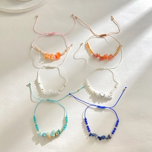 Detail of colorful handmade braided bracelets featuring natural tumbled crystal stones
