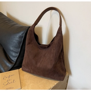Close-up of vintage dark brown suede shoulder bag on stone tabletop with book decoration