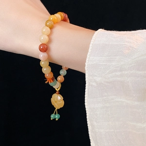 Macro detail of multi-color jade bead bracelet with yellow flower pendant on wrist