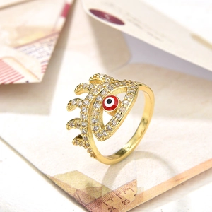 Macro detail of gold eye ring with red enamel and sparkling zircon stones on vintage paper