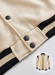 Detail view of the heavy-duty ribbed hem and snap button closure on a beige varsity jacket