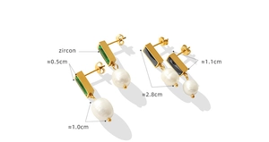 Detail view of gold earrings with green and black zircons and white freshwater pearls
