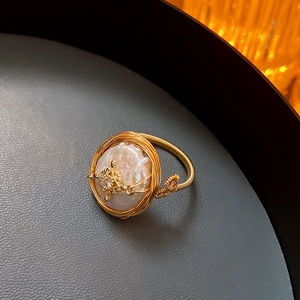 Dettaglio macro di anello con perla barocca, filo d'oro e stella di zircone