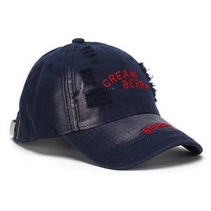 Close-up of navy blue distressed baseball cap with red Cream Berry embroidery detail