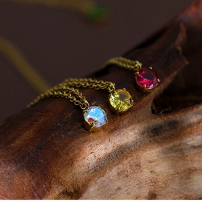 Detailed view of three round-cut zircon necklaces in gold finish on wood blocks