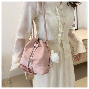 Pink pleated bucket bag detail with metal chain strap and white plush pompom charm