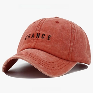 Detail of rust red washed cotton baseball cap featuring black CHANCE embroidery