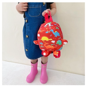 Detailed view of kids red dinosaur backpack with colorful patterns and white zippers