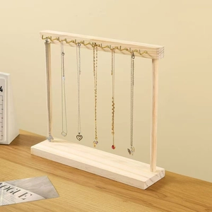 Detail of wooden necklace display stand with gold metal hooks on a wooden table