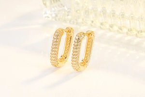 Dettaglio macro di orecchini a U dorati con diamanti micro-pave e una finitura di lusso
