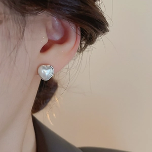 Gros plan de boucles d'oreilles perles en cœur avec bordure argentée sur modèle