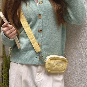 Yellow quilted crossbody bag with white bow embroidery styled with a mint green cardigan